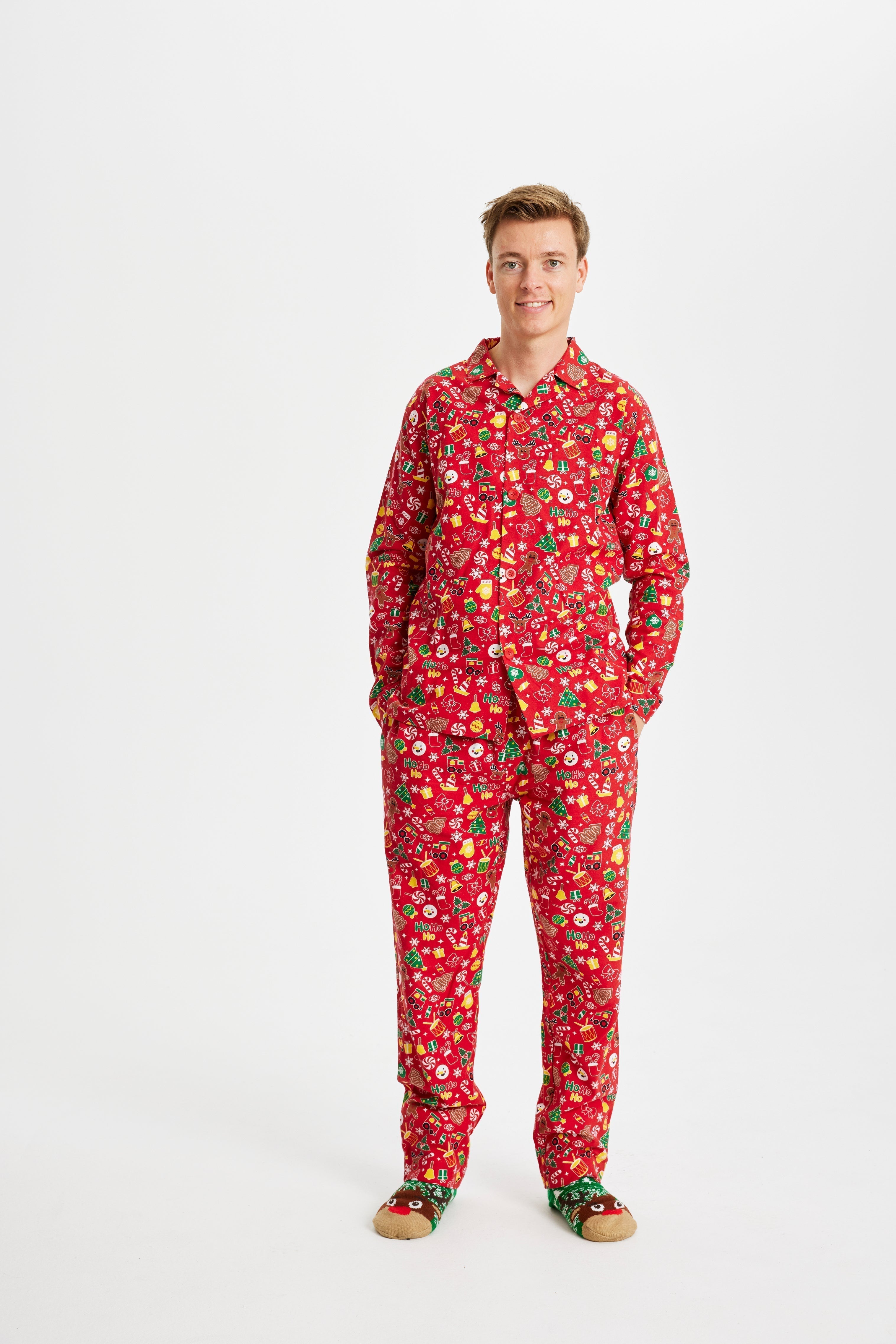 Un homme, les mains dans les poches, portant un pyjama de Noël rouge avec un imprimé de Noël.